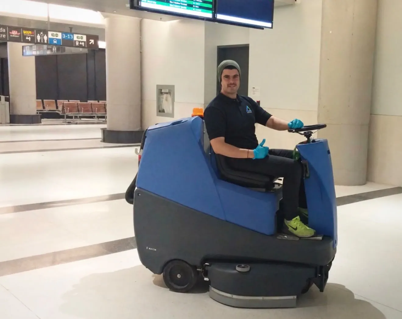 A ride-on floor scrubber in a large public hall